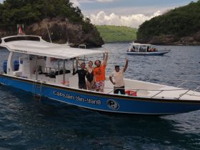 A cheerful group poses on the deck of the 'Captain Yin-Yang' boat during a snorkeling tour, showcasing the fun and adventure of exploring the ocean together.
