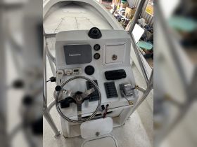 The helm of a boat featuring a sleek console with various controls and instruments, ideal for navigating the waters.