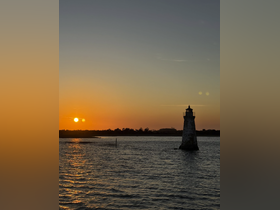 A stunning sunset casts a warm glow over a lighthouse, creating a picturesque scene perfect for evening boat trips and coastal explorations.