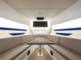 A sleek and modern interior view of a boat's cabin featuring comfortable seating and a dining table, perfect for relaxing and enjoying meals while on the water.