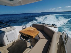 A stylish interior view of a boat's seating area, featuring a polished table and comfortable cushions, perfect for relaxing while cruising the open waters.
