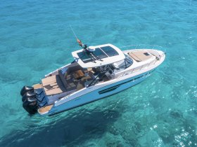 A stunning aerial view of a sleek yacht cruising through crystal-clear waters, showcasing its elegant design and spacious deck — perfect for luxury outings on the sea.