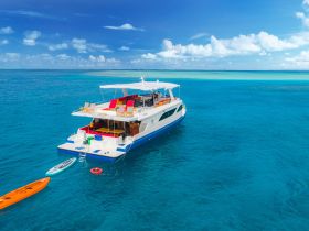 A stunning aerial view of a spacious catamaran cruising through crystal-clear turquoise waters, perfect for luxury charters and island adventures.