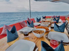 A beautifully arranged dining table on a boat featuring a variety of delicious dishes and drinks, perfect for enjoying a meal while cruising on the open water.