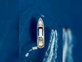 An aerial view of a luxurious yacht surrounded by water activities, including paddleboarding and jet skiing, showcasing the perfect day on the water.