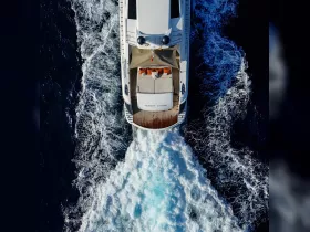 A stunning aerial view of a sleek yacht cruising through deep blue waters, showcasing its elegant design and powerful wake.