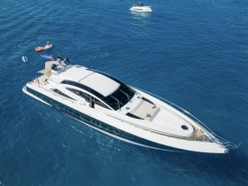 A luxurious yacht navigates through clear blue waters, with guests enjoying paddleboarding nearby — perfect for summer adventures on the water.
