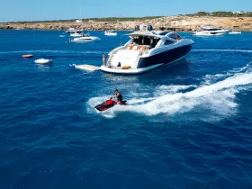 A thrilling moment captured as a rider enjoys jet skiing in vibrant blue waters, with a luxurious boat anchored nearby — perfect for adventure seekers on a sunny day.
