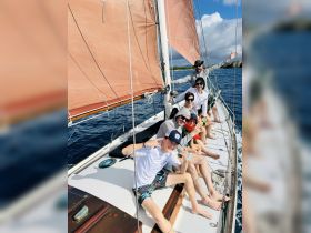 A lively group enjoys a sailing adventure on the ocean, showcasing smiles and camaraderie aboard the boat — perfect for family outings or group fun.
