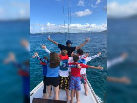 A joyful group of children and an adult enjoy a fun moment on a boat, celebrating the beauty of the ocean and creating lasting memories together.