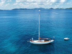 A stunning aerial view of a sailboat anchored in crystal-clear waters, surrounded by picturesque islands — perfect for sailing enthusiasts and tropical getaways.