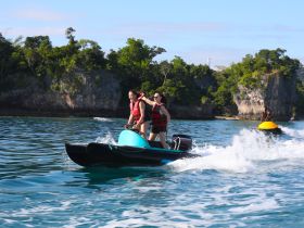A couple enjoys an exhilarating ride on a jet ski, creating waves and laughter in the beautiful turquoise waters — perfect for adventure seekers.