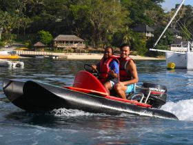 A joyful duo enjoys a thrilling ride on a jet ski, showcasing the excitement of water activities in a beautiful tropical setting.