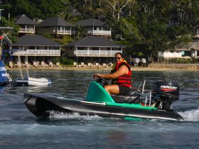 A woman enjoys an exhilarating ride on a jet ski, showcasing the thrill of water sports in a scenic coastal setting.