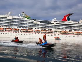 A thrilling scene of guests enjoying jet skiing in front of the Carnival Splendor, showcasing the excitement of water activities during a cruise.