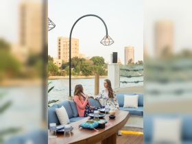 Two friends enjoy a conversation in a stylish dining area on a boat, with a scenic river view in the background — perfect for social gatherings and celebrations.