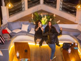 Guests relax in a stylish lounge area aboard a boat, showcasing comfortable seating and a cozy atmosphere perfect for socializing.