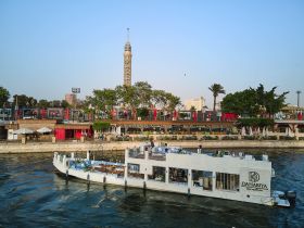 A stunning dahabiya boat glides along the Nile, showcasing its elegant design against the backdrop of Cairo's iconic landmarks.