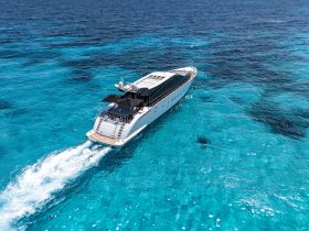 A stunning aerial view of a sleek yacht cruising through crystal-clear turquoise waters, perfect for luxury charters and island adventures.