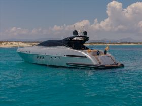 A stunning yacht glides through crystal-clear waters, showcasing its sleek design against a picturesque backdrop of sandy shores and distant mountains.