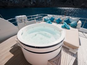 A luxurious jacuzzi on the deck of a boat, surrounded by plush seating and vibrant cushions, perfect for relaxation while enjoying the stunning ocean views.
