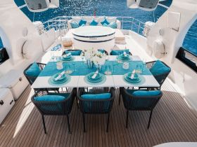 An elegantly set dining area on a yacht, featuring a beautiful table arrangement with turquoise accents and a jacuzzi in the background, perfect for luxurious onboard dining experiences.