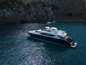 A stunning aerial view of a luxurious yacht cruising through crystal-clear waters, surrounded by scenic cliffs — perfect for upscale boating adventures.