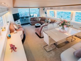 A beautifully designed interior of a luxury yacht featuring a spacious seating area and dining table, perfect for relaxing and entertaining while enjoying the ocean views.