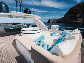 A beautifully designed lounge area on a yacht, featuring comfortable seating and a dining setup, perfect for enjoying meals and relaxation while cruising.