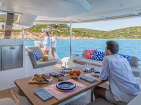 A couple enjoys a delightful dining experience on a boat, surrounded by stunning coastal scenery — perfect for romantic getaways or leisurely afternoons on the water.