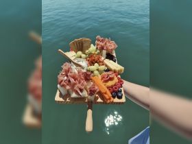 A beautifully arranged charcuterie board featuring an assortment of meats, cheeses, and fresh fruits, perfect for enjoying on a boat trip.