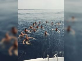 A lively group enjoys a refreshing swim in the open ocean, showcasing the fun and camaraderie of a perfect day on the water.