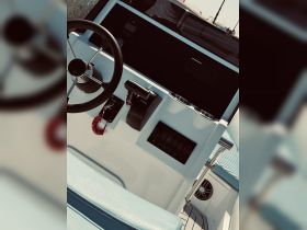 A detailed view of the helm and console area inside a boat, showcasing the steering wheel and control panel — perfect for understanding the boat's operational features.