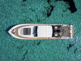 A stunning aerial view of a luxurious yacht cruising over crystal-clear waters, showcasing its elegant design and spacious deck, ideal for summer adventures.
