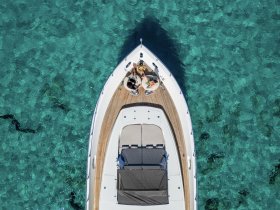 An aerial view of a couple enjoying a relaxing moment on the deck of a boat, surrounded by stunning clear waters — perfect for romantic getaways or leisure trips.