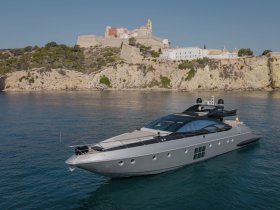 A stunning aerial view of a sleek yacht anchored near a picturesque coastal town, showcasing the beauty of luxury boating against a scenic backdrop.