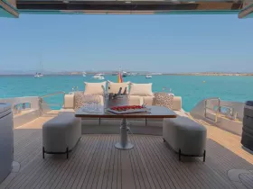 A beautifully designed lounge area on a yacht, featuring comfortable seating and a dining table, perfect for enjoying meals while taking in stunning ocean views.