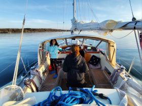 A young girl and an adult enjoy sailing together on a calm day, showcasing the joy of family bonding on the water.
