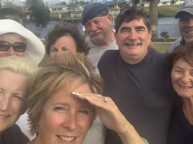 A cheerful group of friends poses for a selfie by the water, capturing a moment of joy and camaraderie during their boating adventure.