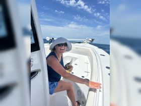 A joyful woman enjoys a refreshing drink while relaxing on a boat, capturing the essence of fun and relaxation on the water.
