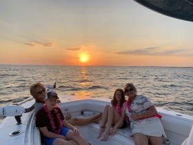 A joyful family enjoys a sunset cruise on their boat, capturing a perfect moment with drinks in hand and smiles all around.