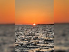 A stunning sunset over the water, creating a picturesque scene perfect for romantic evenings or peaceful boat rides.