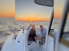 Two friends enjoy a beautiful sunset aboard a boat, capturing the perfect moment for a memorable evening on the water.