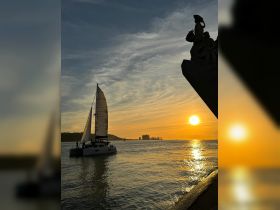 A picturesque sunset view featuring a sailboat gliding across the water, creating a serene atmosphere perfect for evening cruises.
