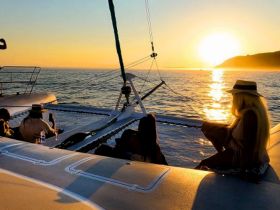 A group enjoys a stunning sunset aboard a catamaran, creating a perfect backdrop for relaxation and celebration on the water.