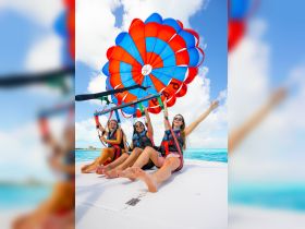 Three friends enjoy an exhilarating parasailing adventure over turquoise waters, capturing the thrill of water sports and group fun.