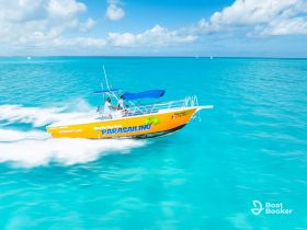 A vibrant parasailing boat speeds through the stunning turquoise waters, showcasing the excitement of water sports in a tropical paradise.