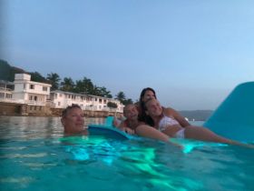 A joyful family enjoys a relaxing swim in the warm waters, capturing a perfect moment of togetherness during their sunset adventure.