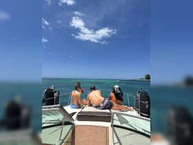 A group enjoys a sunny day on the boat, relaxing and sipping drinks while taking in the stunning ocean views — perfect for a day of fun on the water.