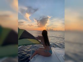 A woman enjoys a stunning sunset view from the bow of a boat, capturing the essence of relaxation and beauty on the water.